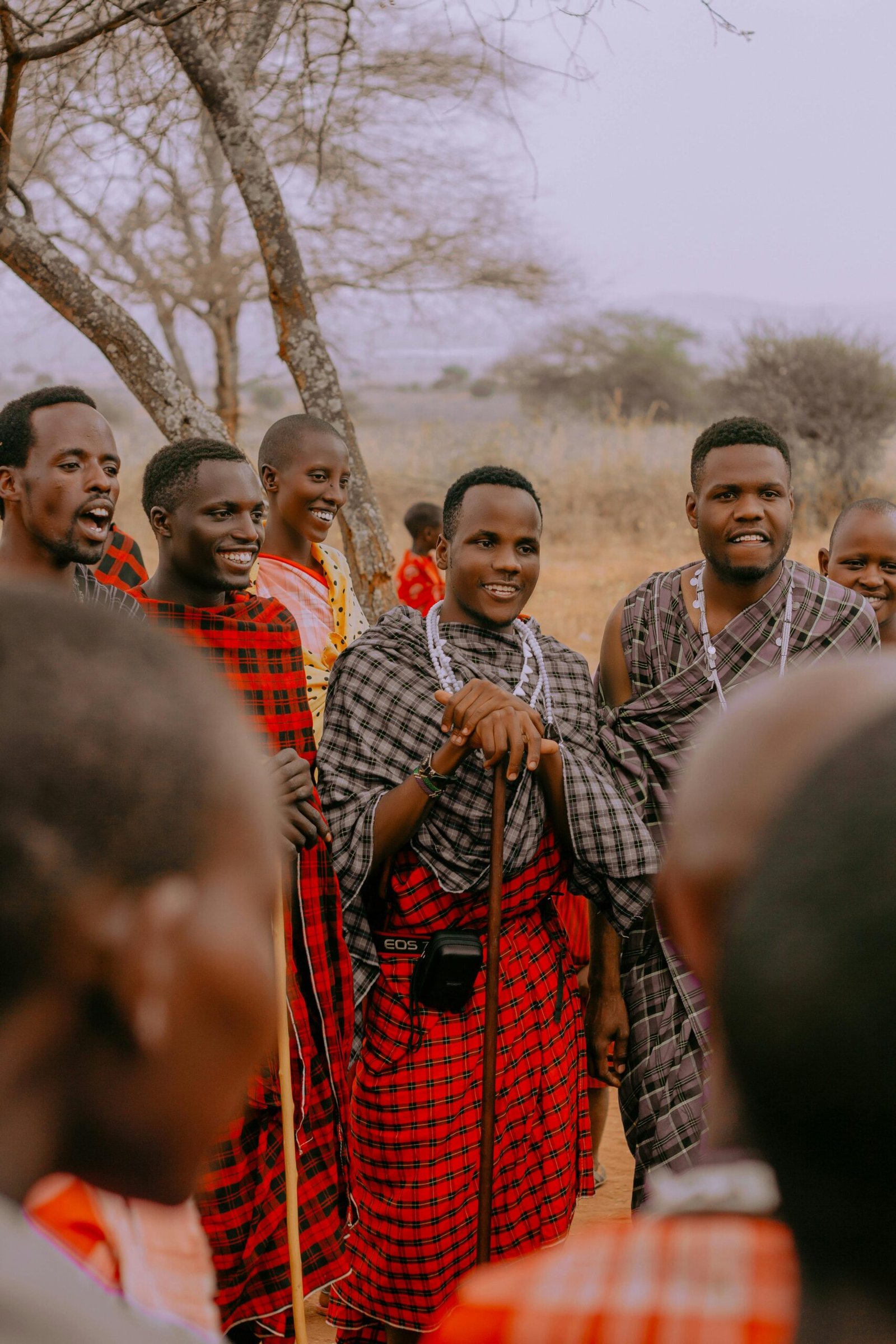 A group of Maasai men wearing traditional clothes in an outdoor setting.