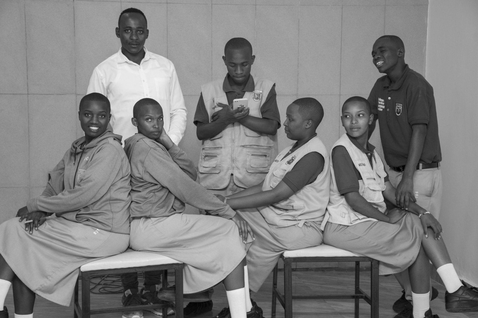 Black and white portrait of school students and teacher in uniform, posing indoors.