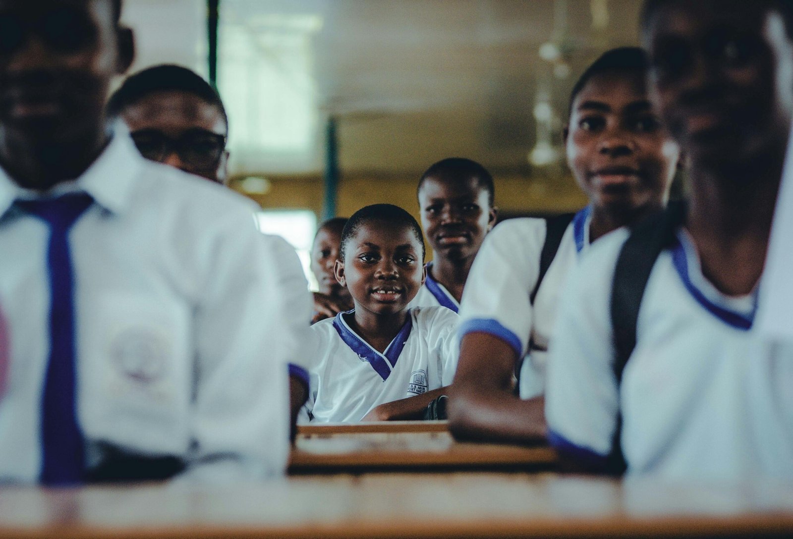 A group of Nigerian schoolchildren in uniform sitting in a classroom, engaging in learning.